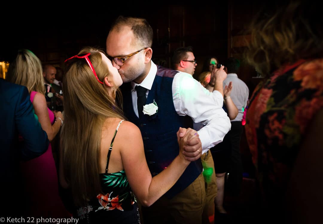 Best man kissing girl friend at candid wedding