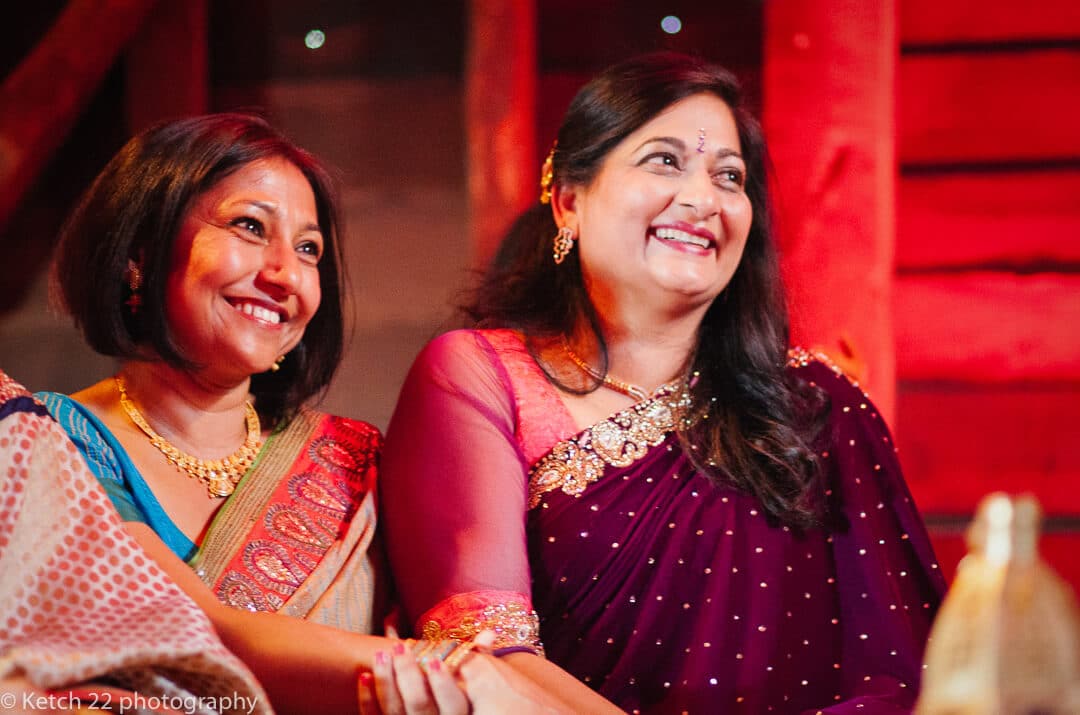 Mums wearing colourful Indian costume laughing at Hindu wedding