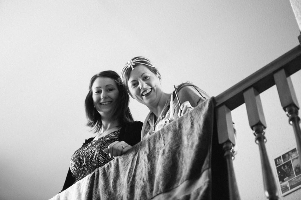 Bride and bridesmaid leaning on banister and smiling at wedding in Shropshire