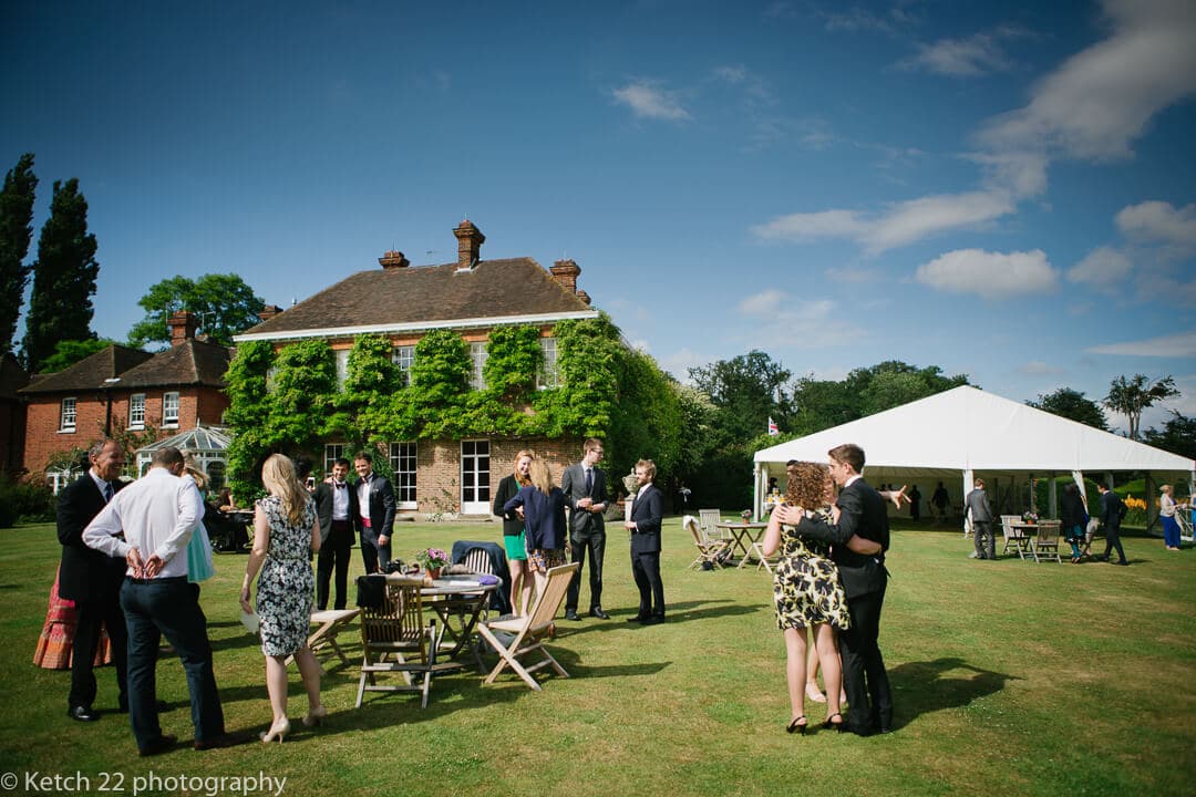 Wedding guests having canapes and drinks on lawn at Micklefield Hall