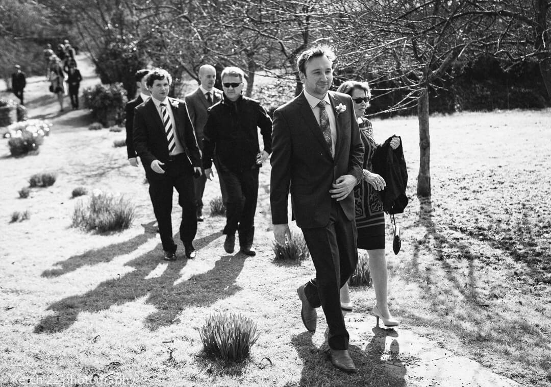 Groom and wedding guests walking to church in Herefordshire