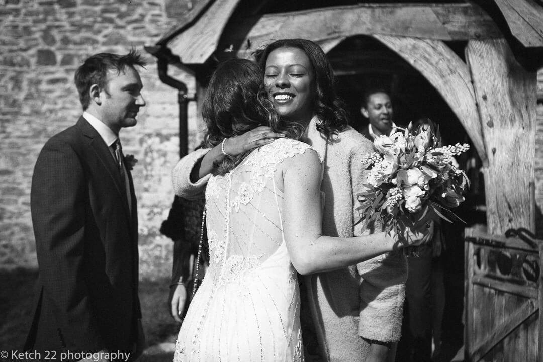 Bride hugging wedding guest outside church in Herefordshire