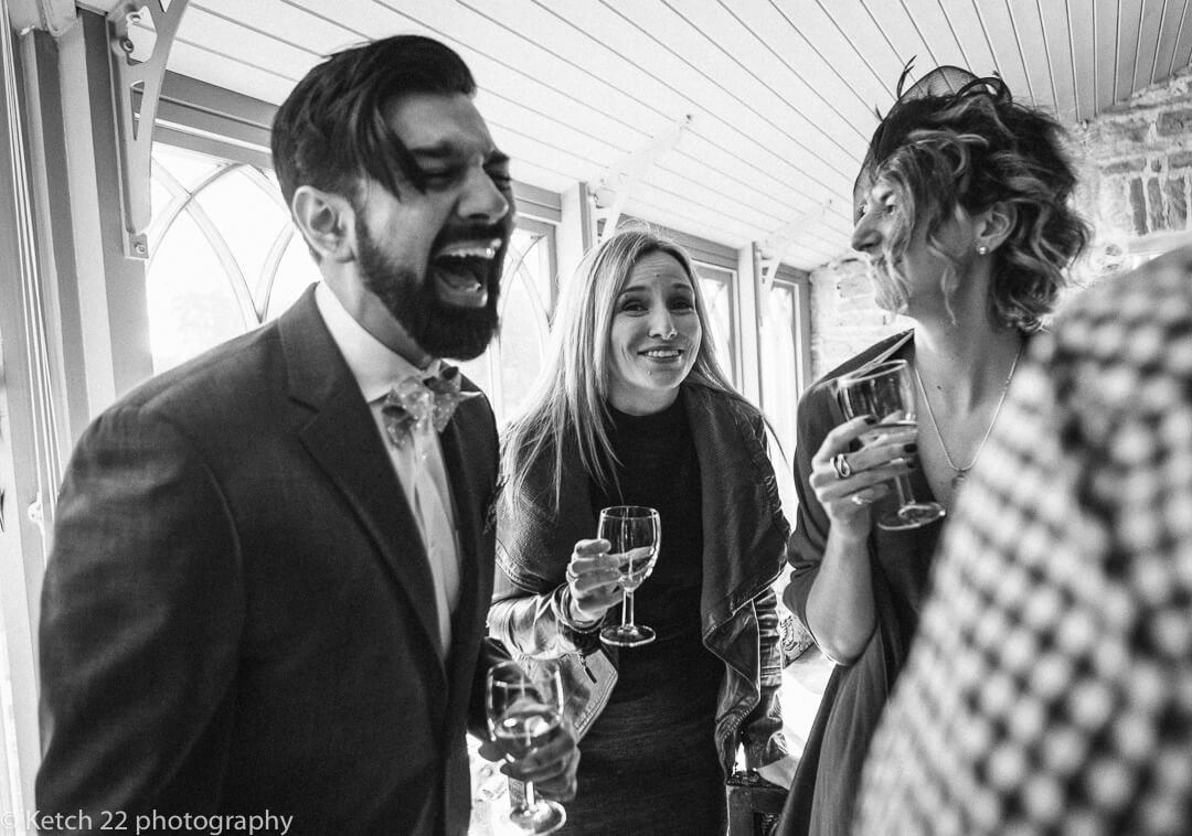 Documentary wedding photo of guests drinking and laughing