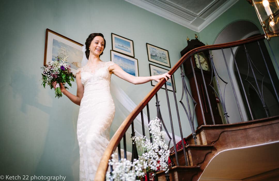 Bride walking downstairs holding flowers at Homme House wedding