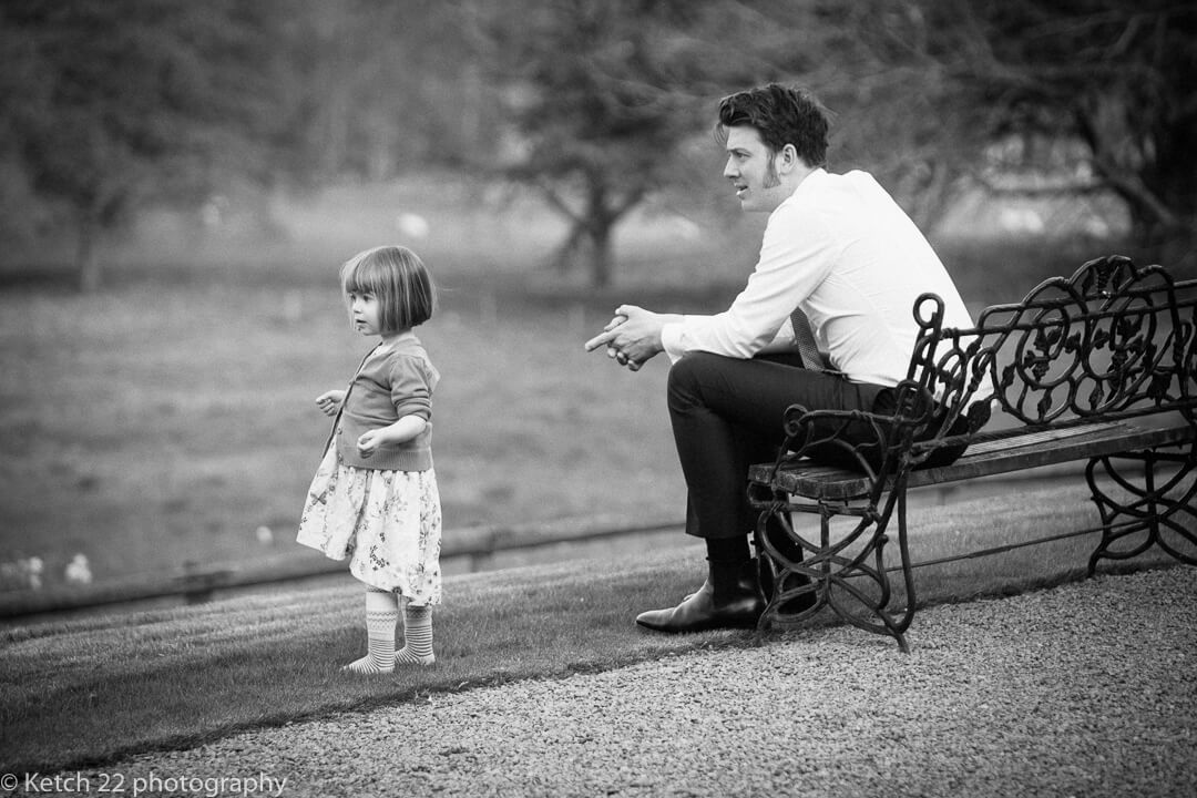 Documentary wedding photo of father and daughter relaxing in garden at wedding