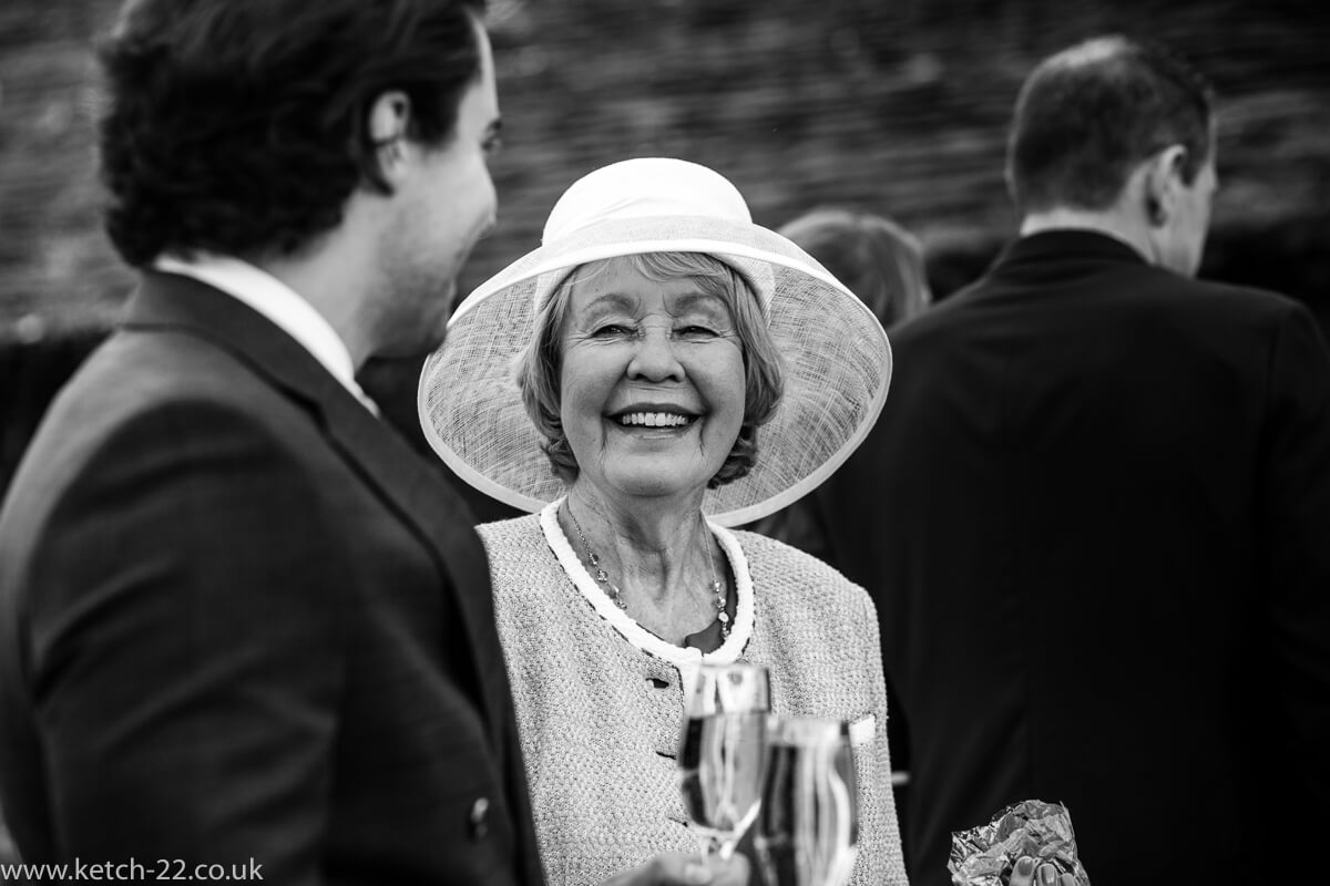 Older lady wedding guest with big white hat chatting