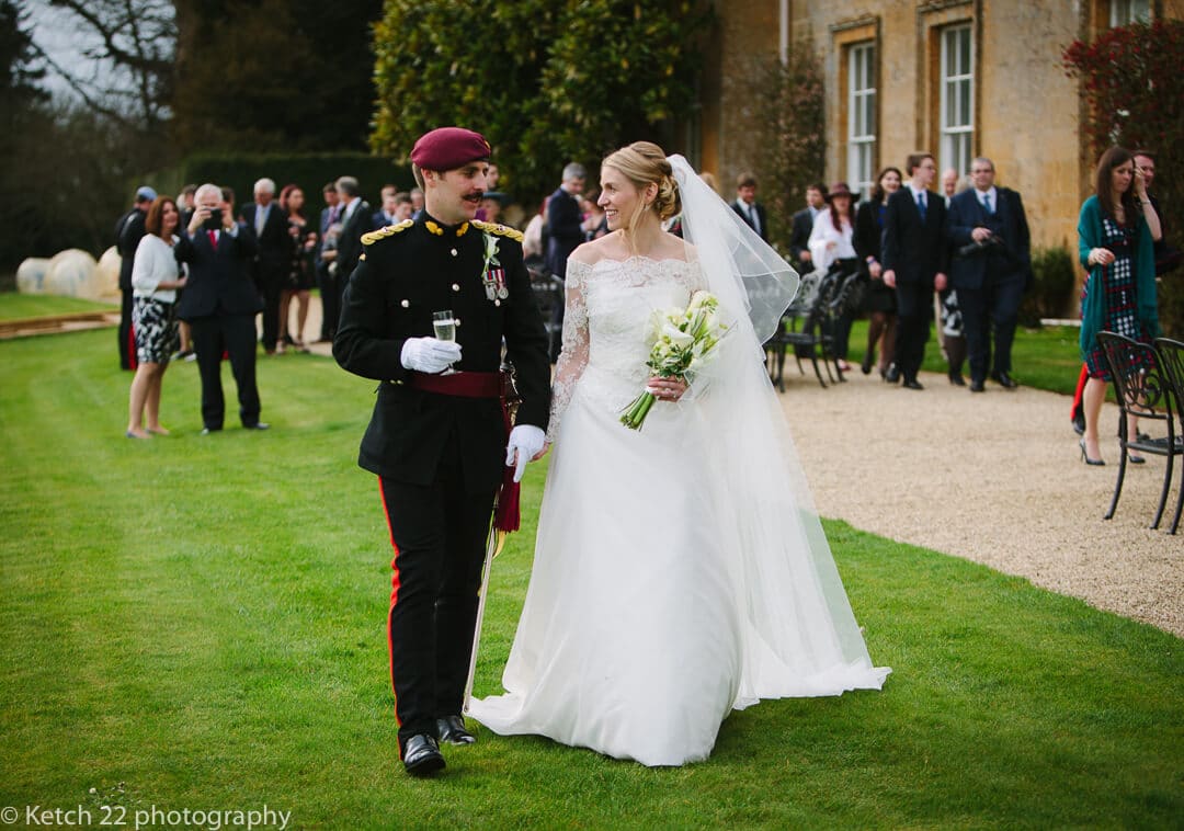 Bride and groom in army uniform walking in front of North Cadbury Court