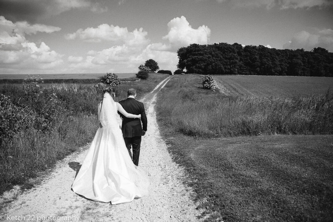 Bride and groom walk down country track at Cripps Stone barn wedding