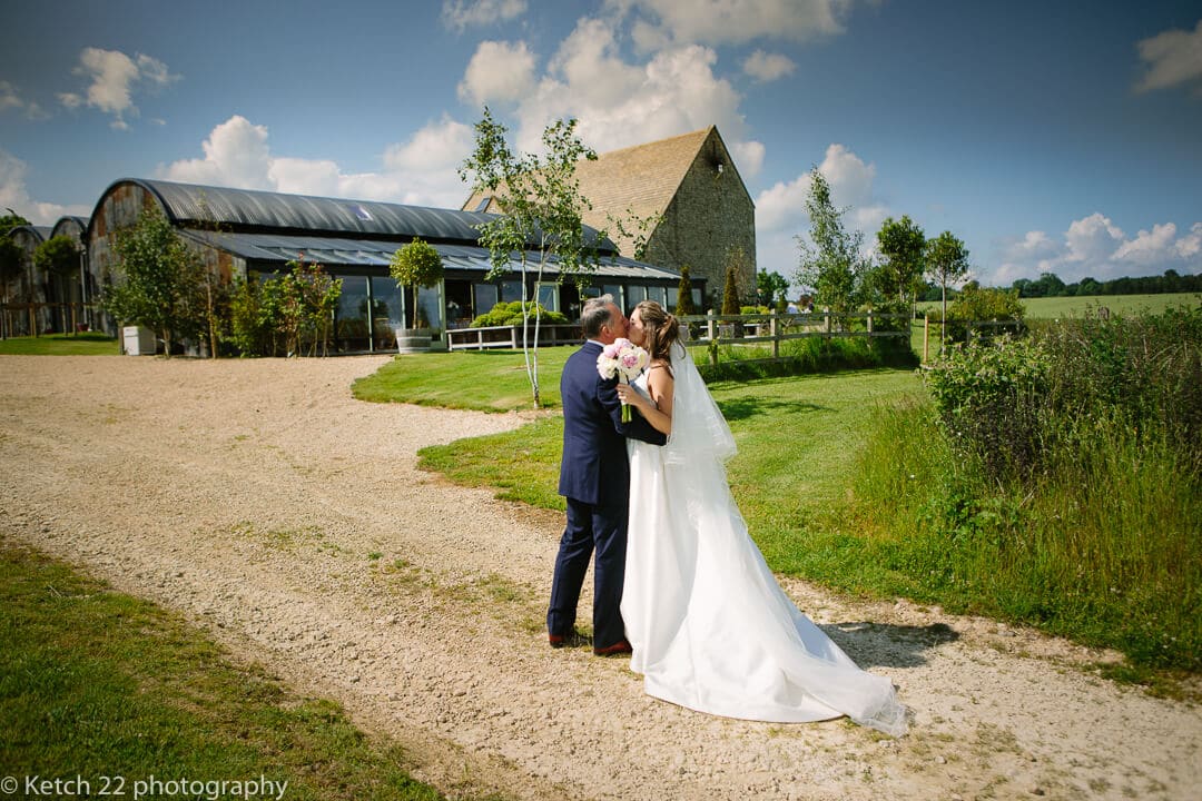 Bride and groom kissing in front of Cripps Stone Barn