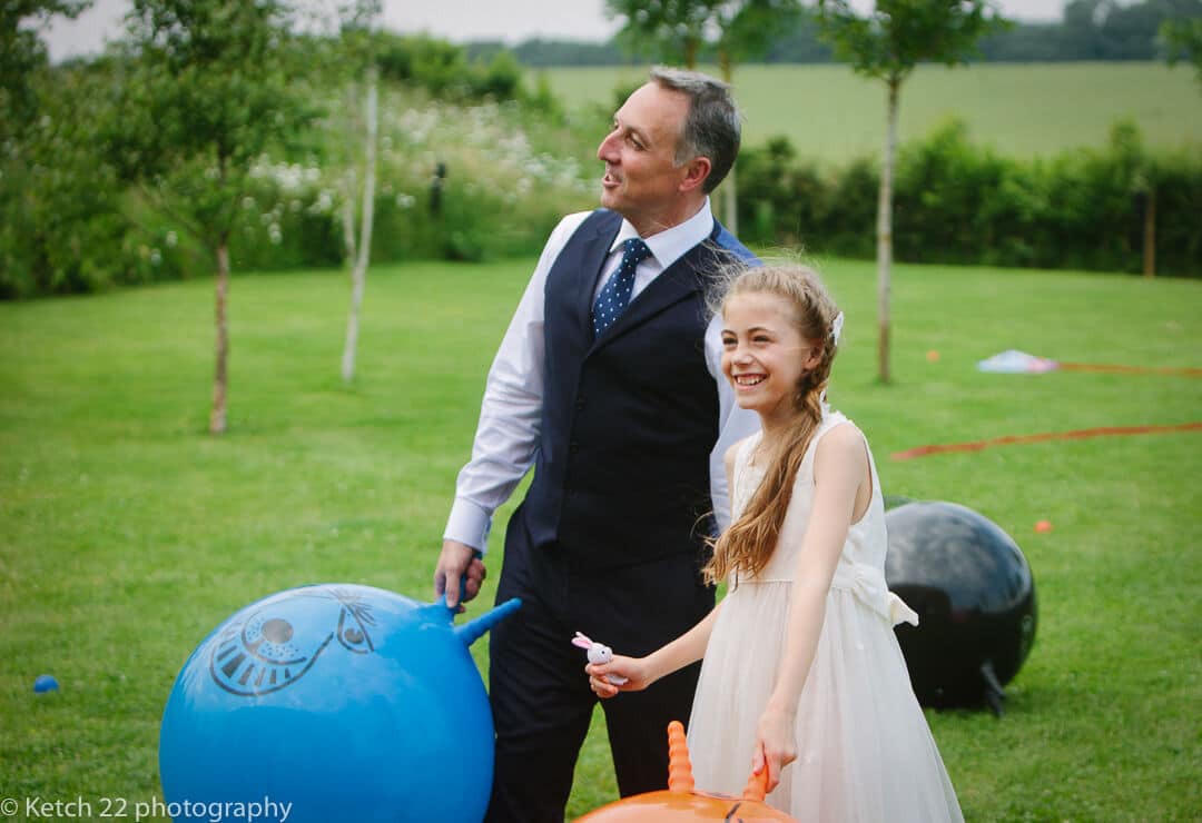 Groom and his daughter playing with space hoppers