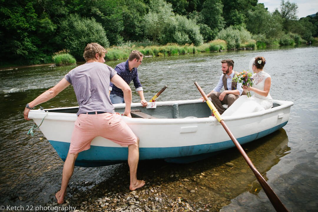 Bride and groom get on rowing boat on river Wye