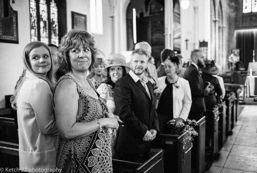 Wedding guests looking at bride enter church