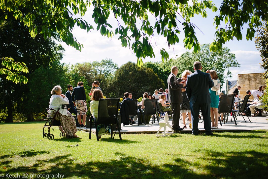 Wedding guests having drinks on lawn at summer wedding in Gloucestershire
