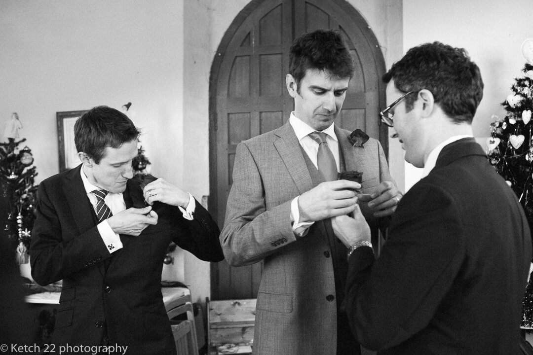Grooms men pinning their flowers on jacket at reportage wedding