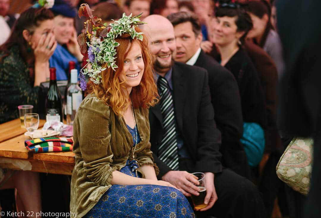 Wedding guest with flowers in her hair watching speechs