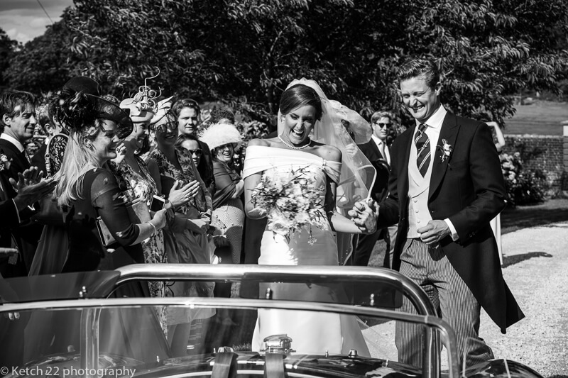 Bride and groom entering sporty wedding car in Dorset