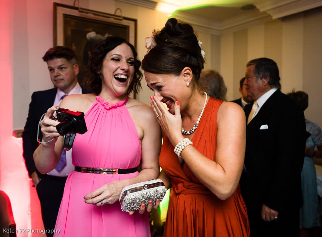 Wedding guests with pink and red dresses laughing at reception