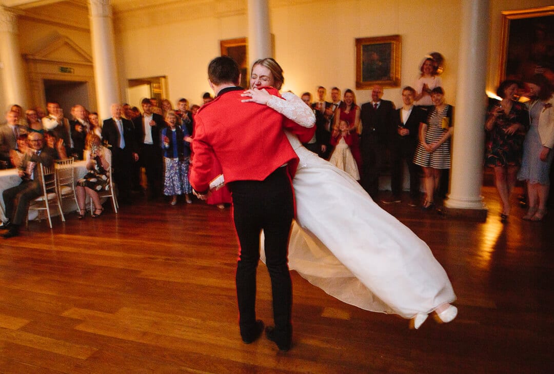 Groom in red army jacket spinning bride at first dance