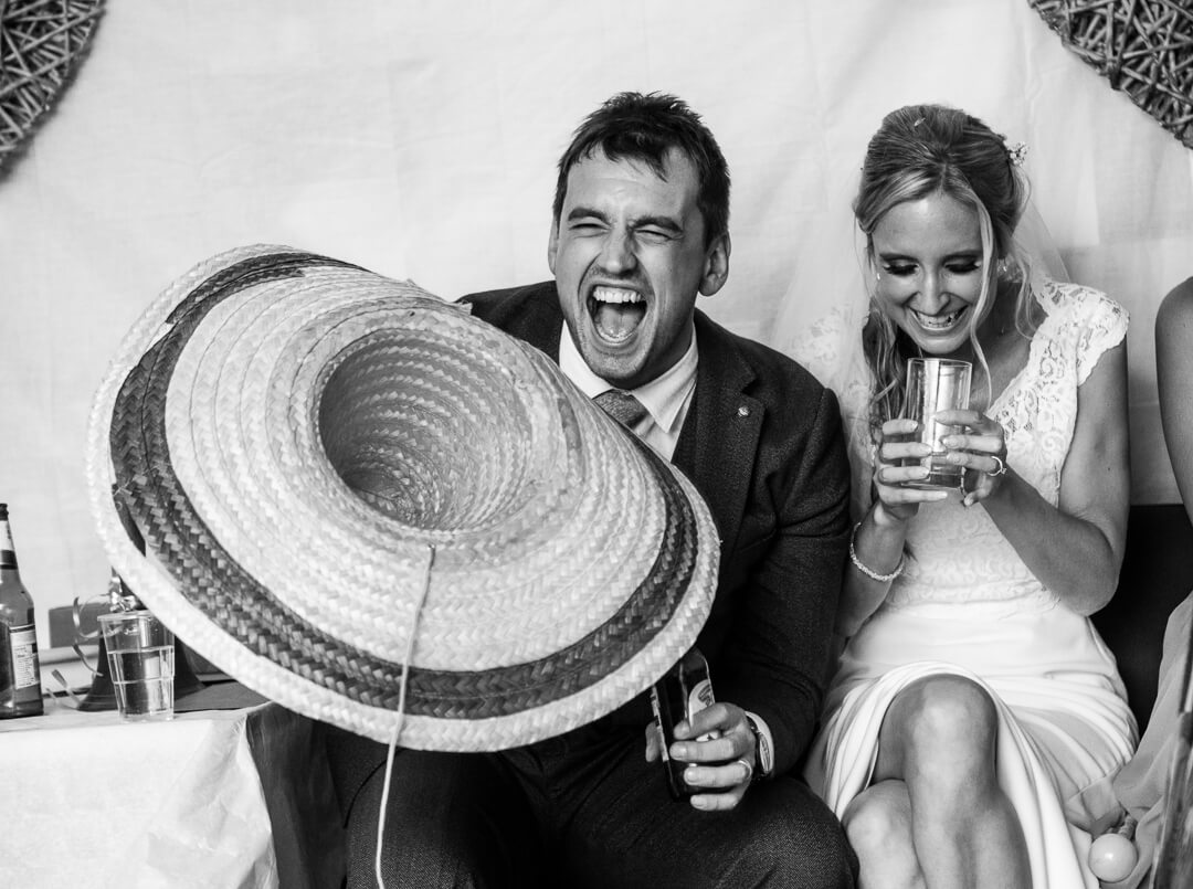 Groom holding mexican hat laughing at best mans wedding speech