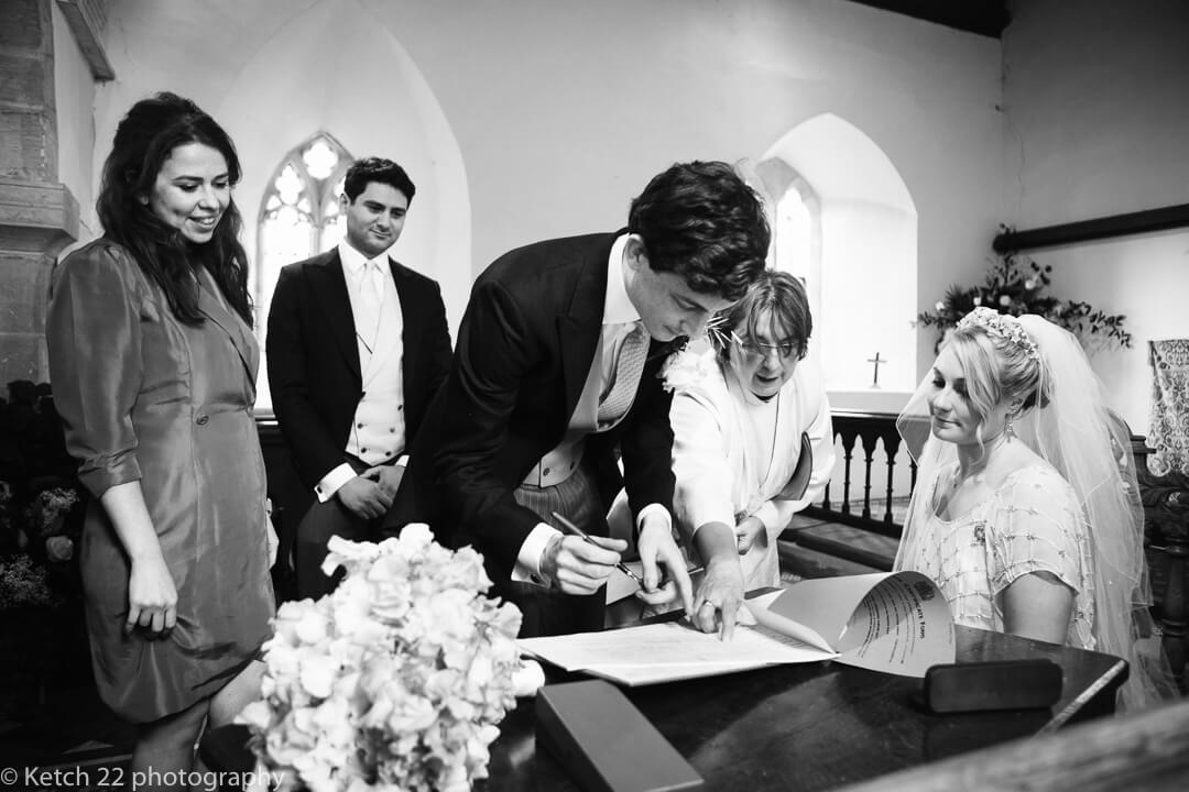 Groom signing registrar at wedding ceremony in Church