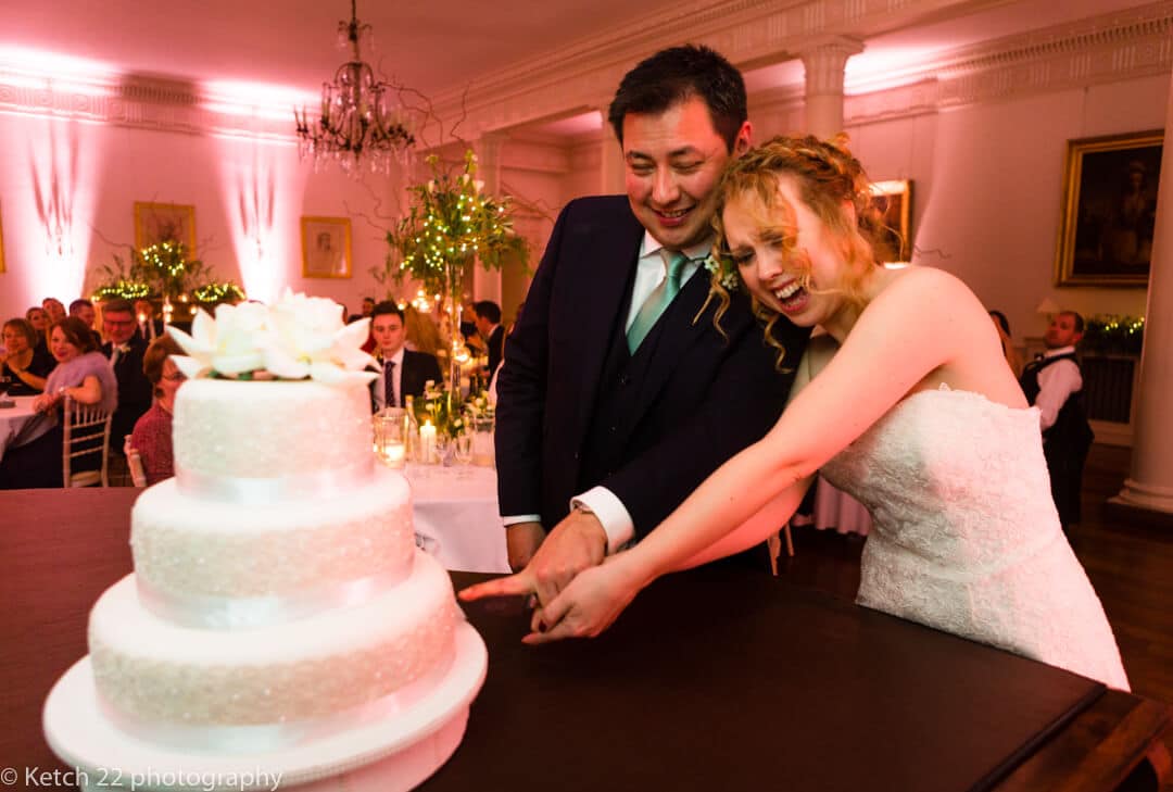 Documentary wedding photo of bride and groom cutting cake