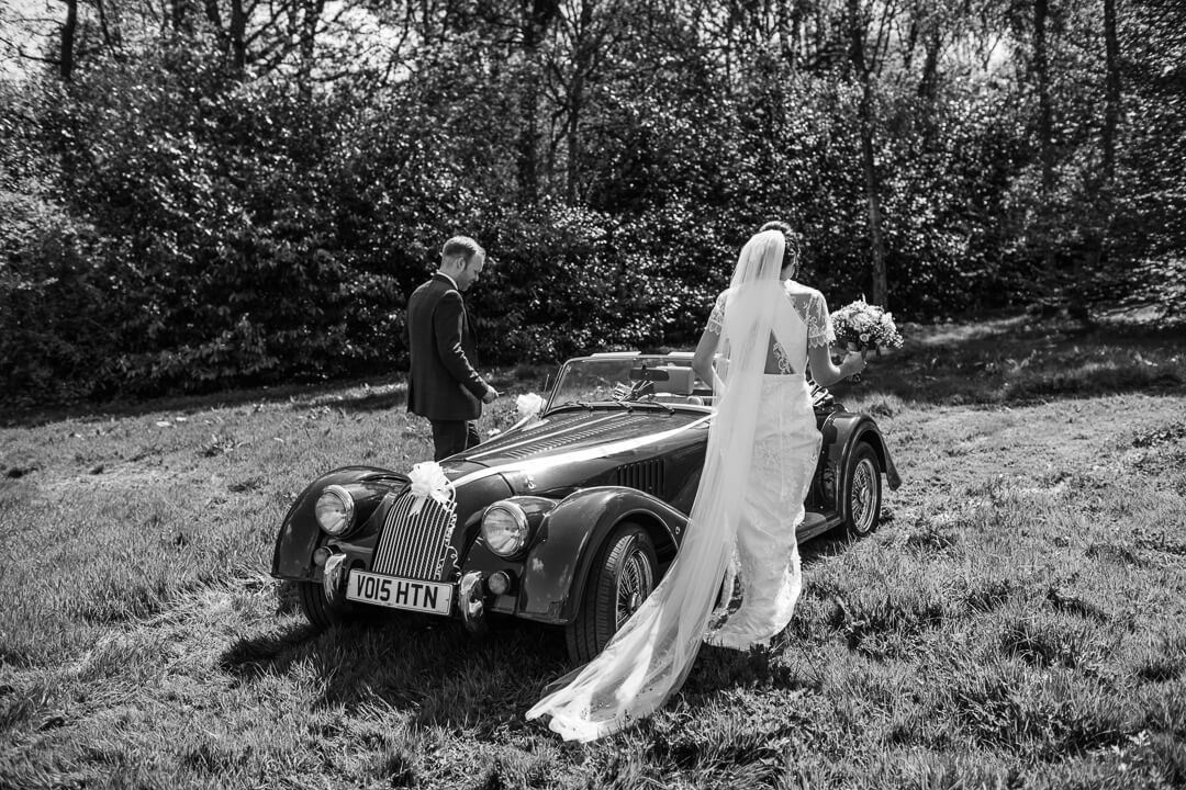 Bride and groom getting into vintage wedding car