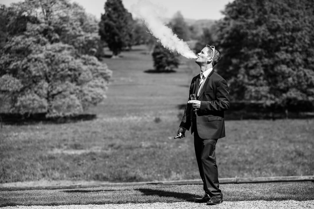 Documentary wedding photo of guest smoking e cigerette