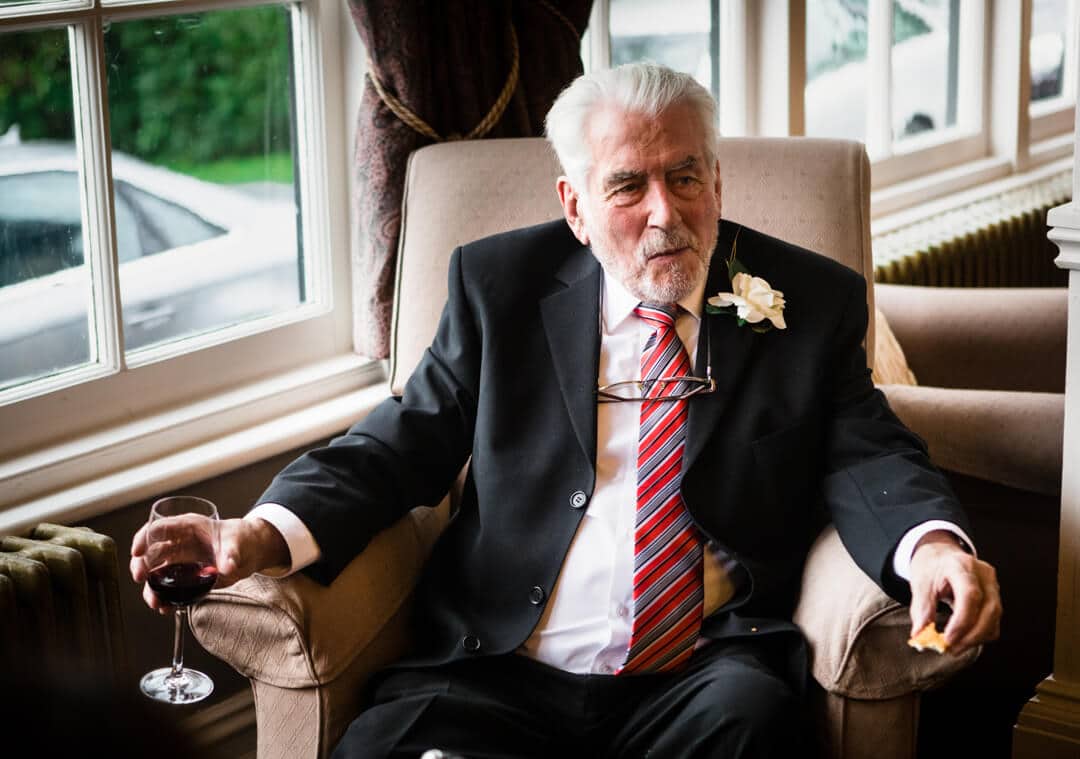 Grandad enjoying glass of wine at wedding