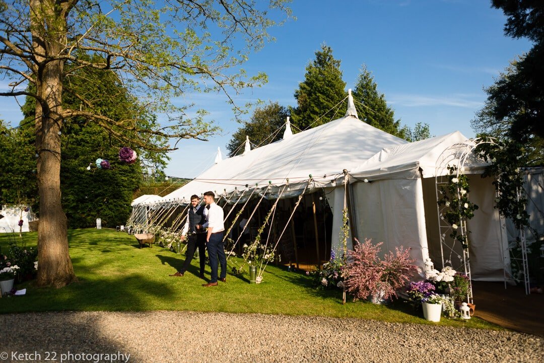 Guests standing outside wedding marquee on sunny evening