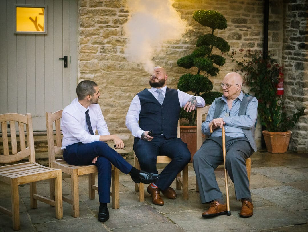 Wedding guest blowing vape into the air at Kingscote Barn