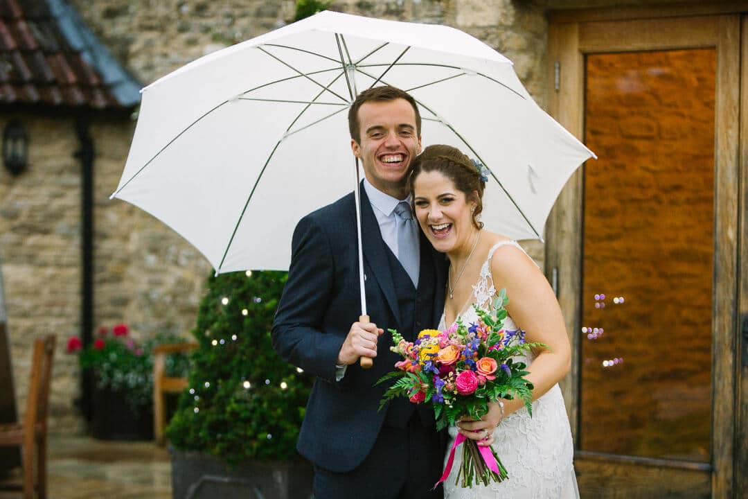 Portrait of bride and groom with umbrella at Kingscote Barn wedding