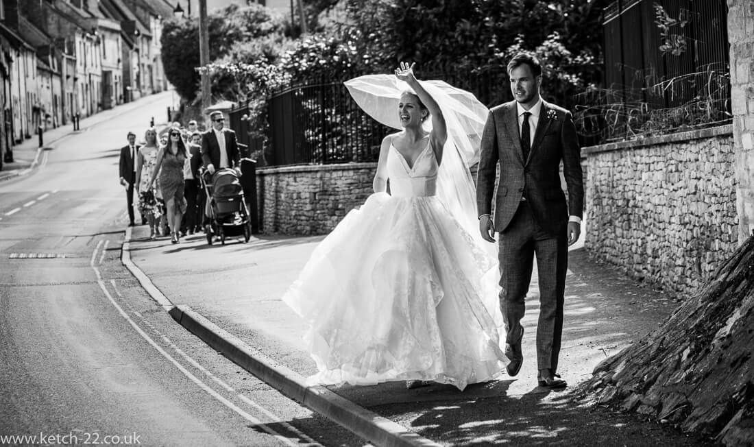 Bride waving to people - Winchcombe wedding photographer
