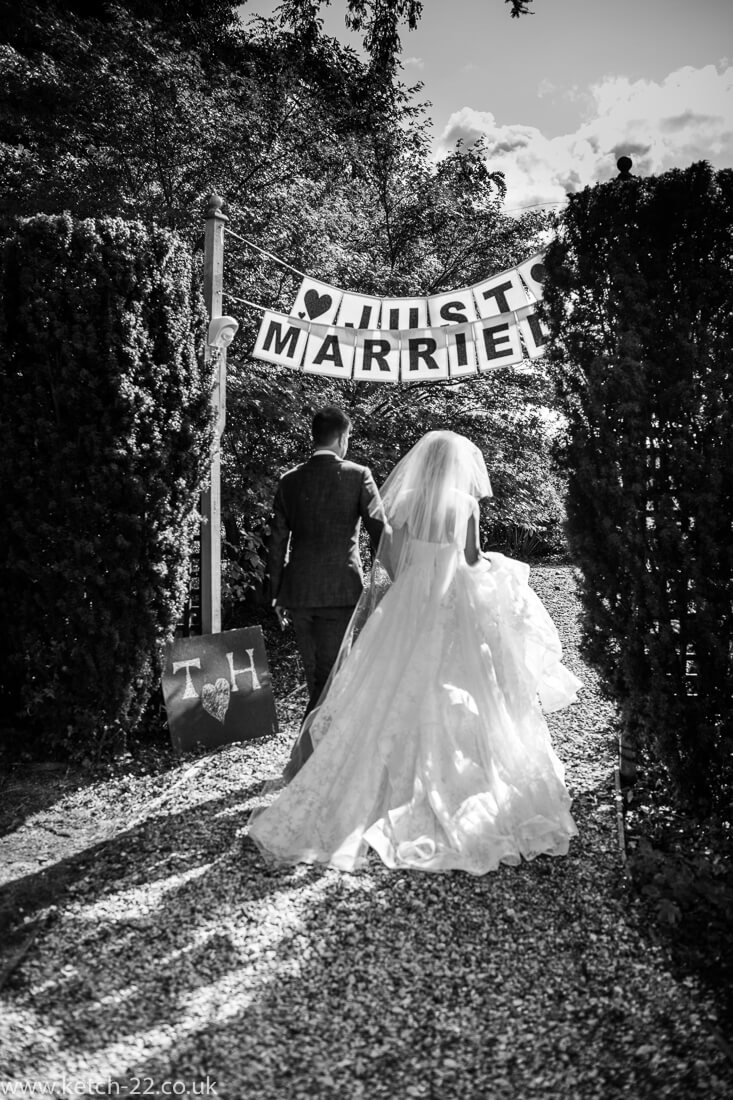 Bride and groom walk under just married banner
