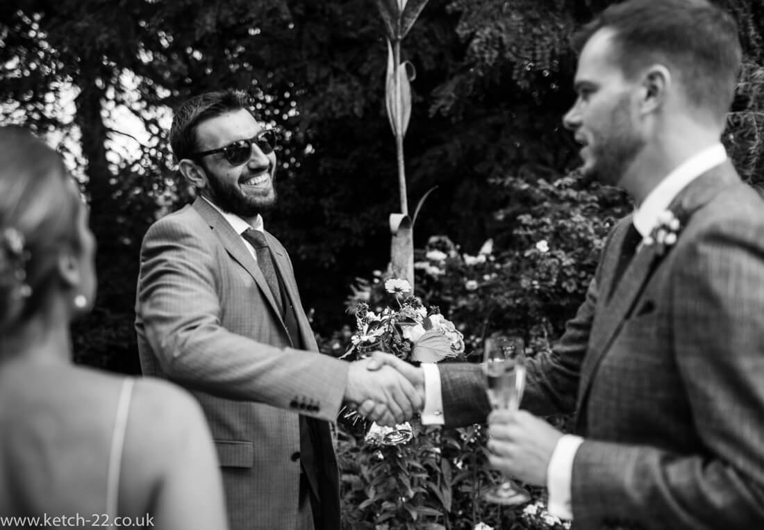 Groom greets his friend at Winchcombe wedding
