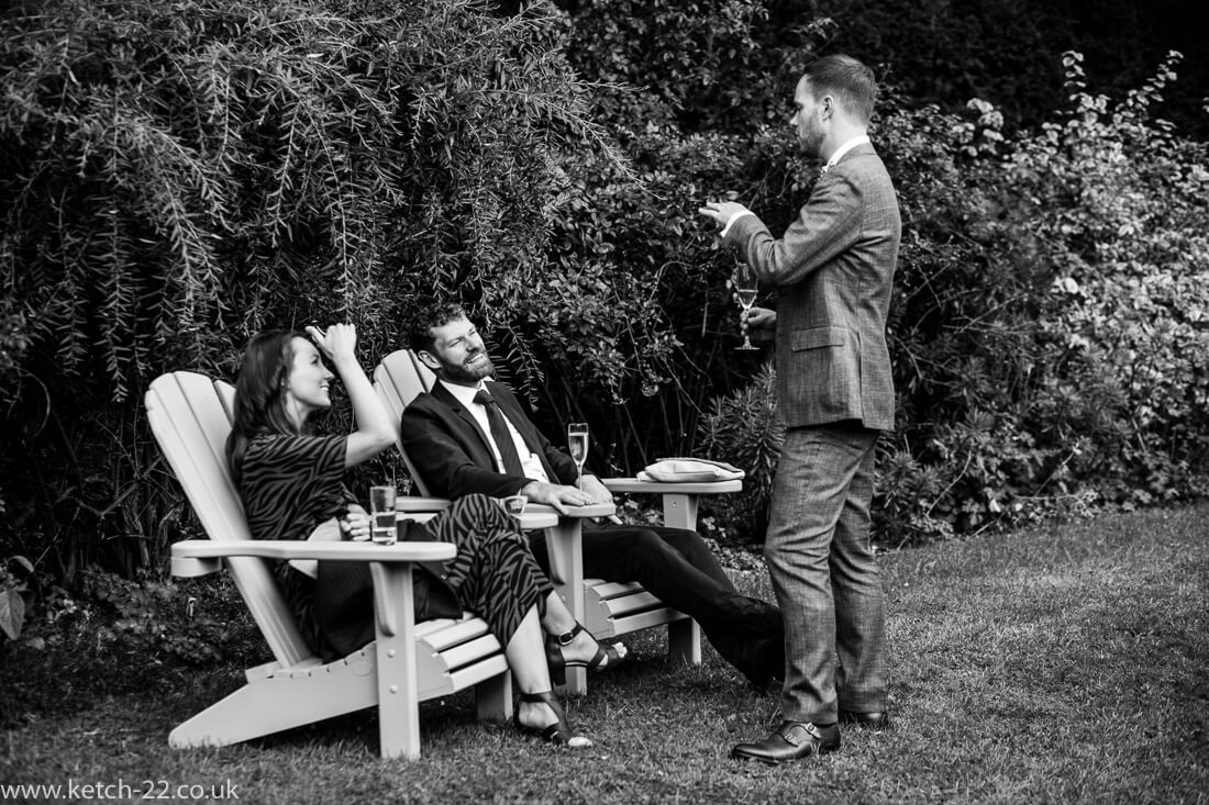 Groom chatting to seated wedding guests in garden