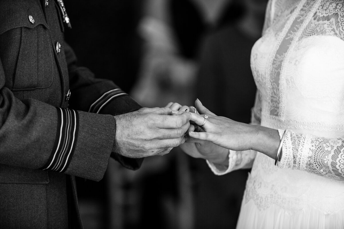 Close up of groom putting wedding rings on brides finger