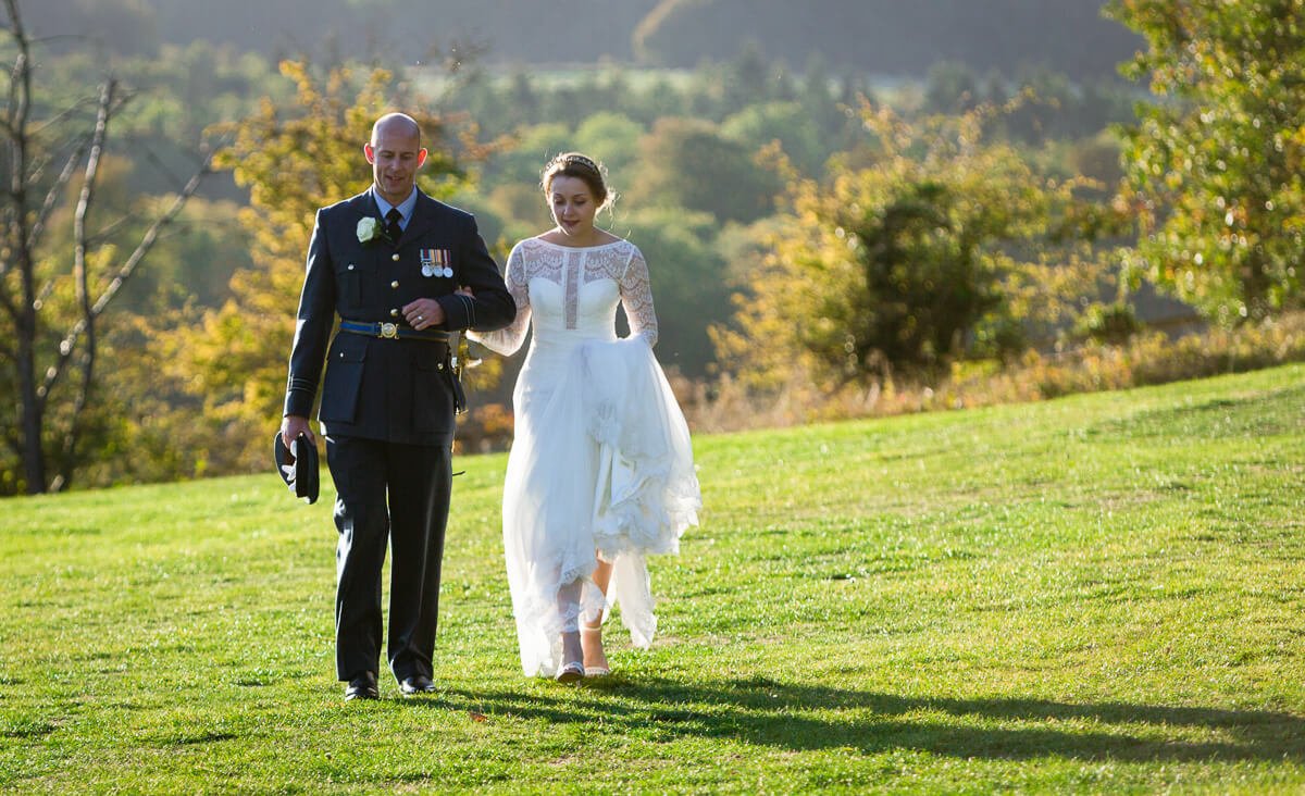 Natural wedding photo of bride and groom walking across garden