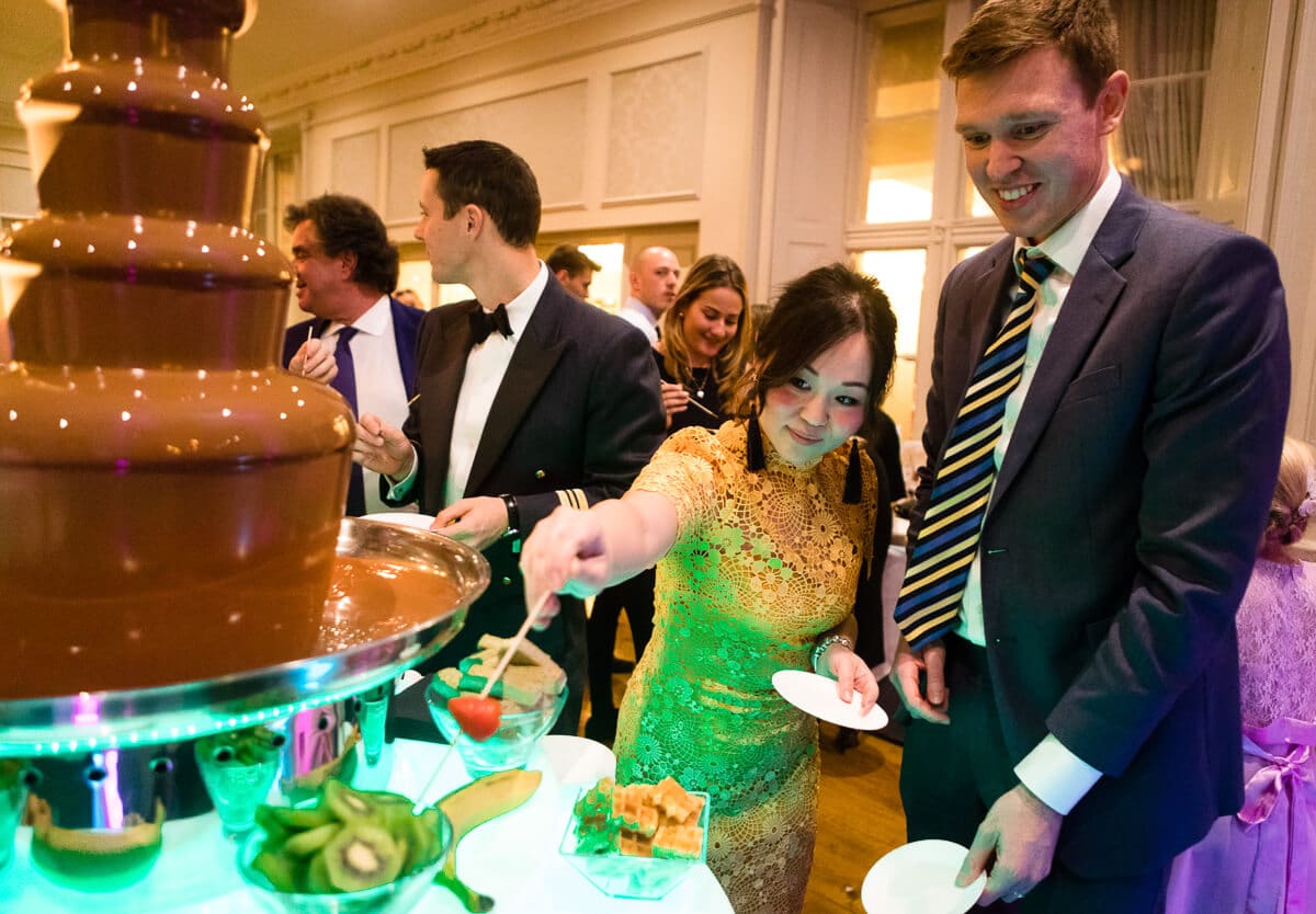 Wedding guests dipping strawberry in chocolate fountain