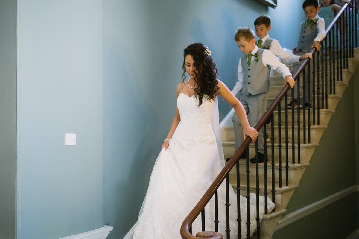 Bride and page boys descending stairs at Summer wedding