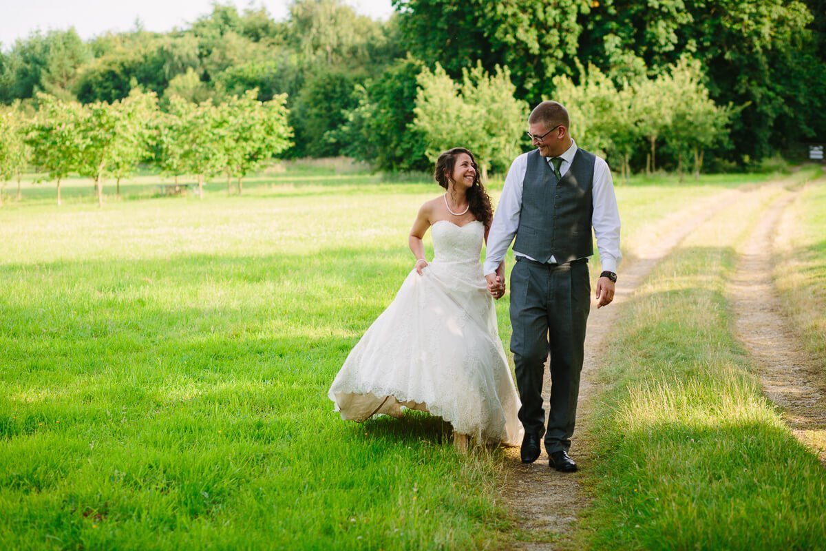 Bride and groom walking in gardens at summer wedding