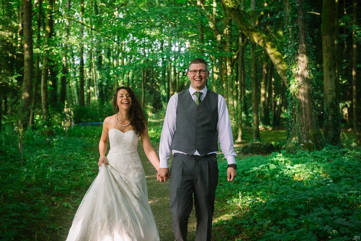 Bride and groom walking in green woods 