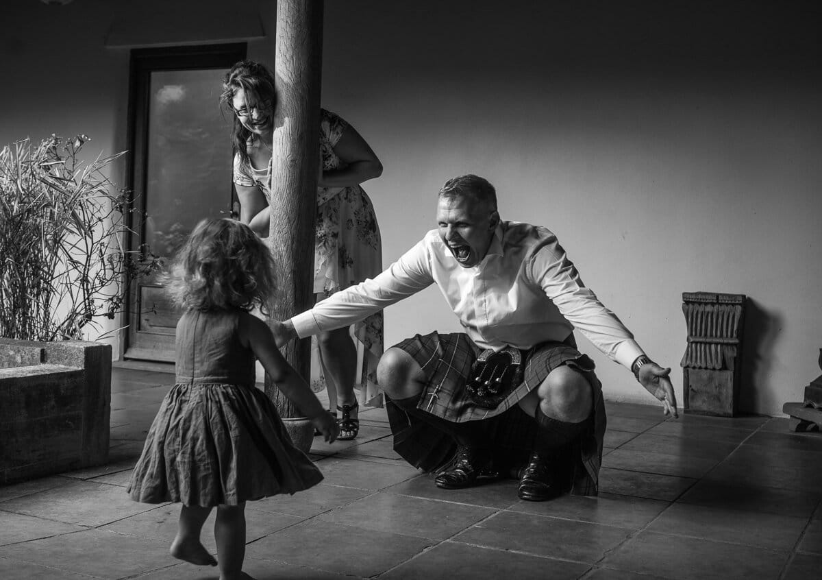 Man wearing kilt playing with his daughter at wedding