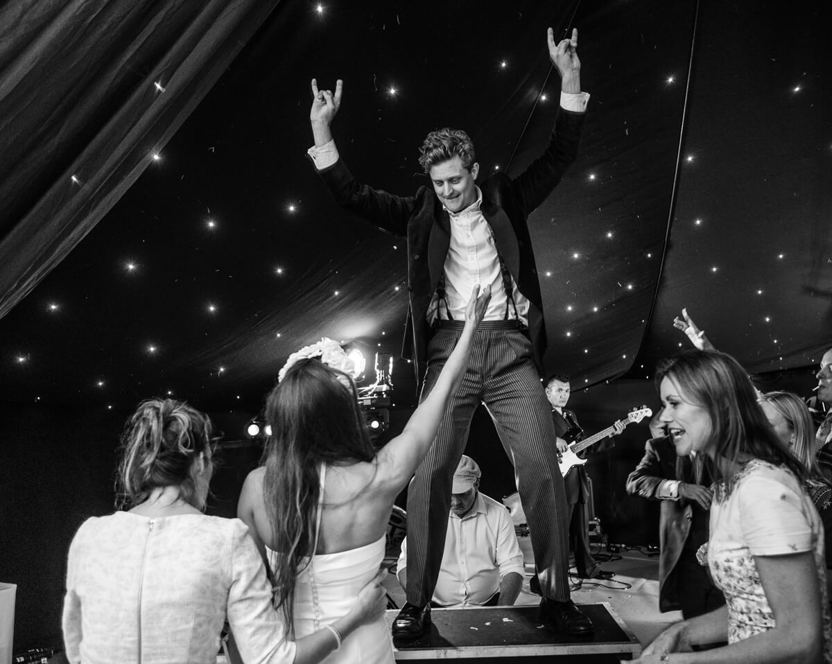 Groom dancing on table at reception