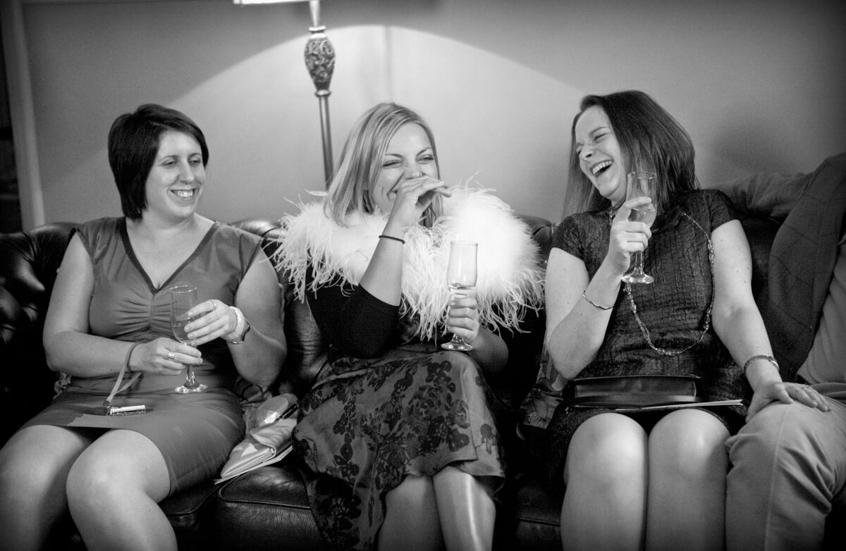 Ladies at wedding laughing on sofa at Lemore Manor Herefordshire