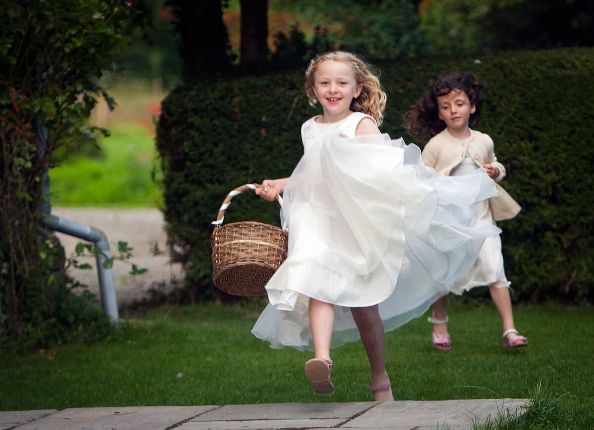 Flower girls running and laughing with basket at Herefordshire wedding