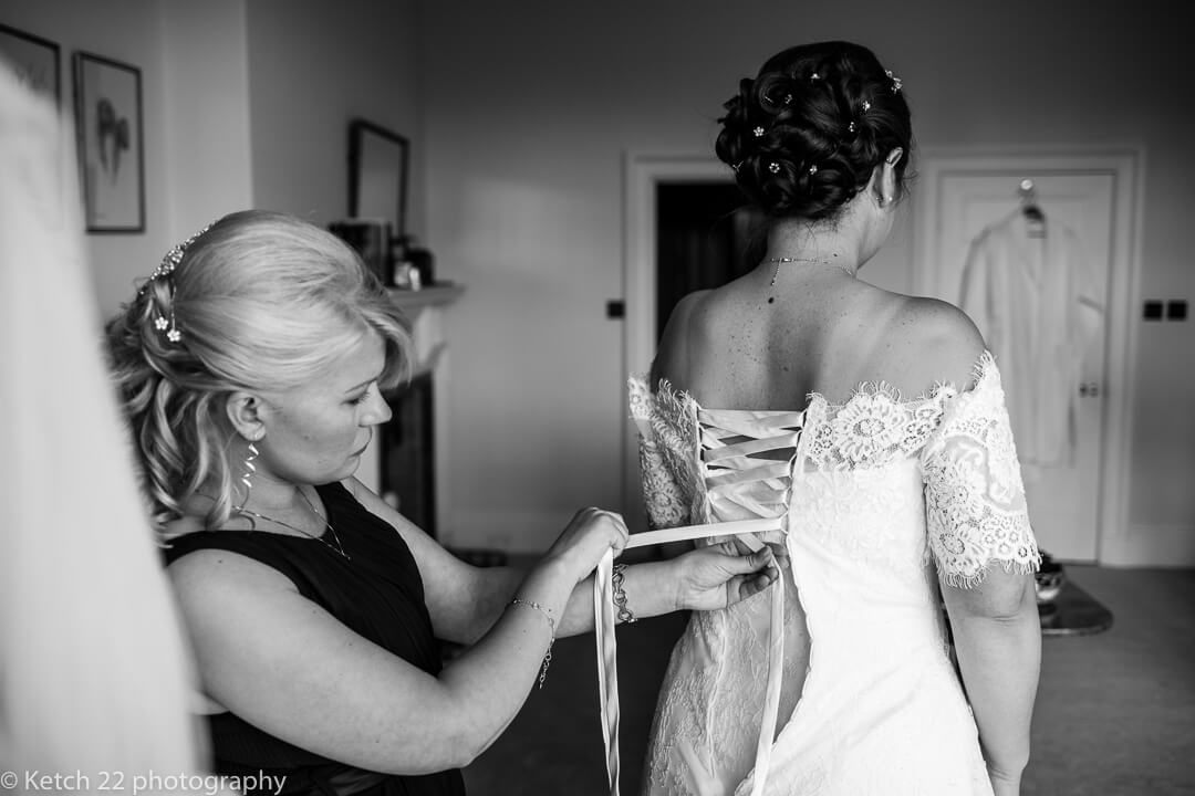 Bride having the back of her wedding dress laced up at bridal preparations