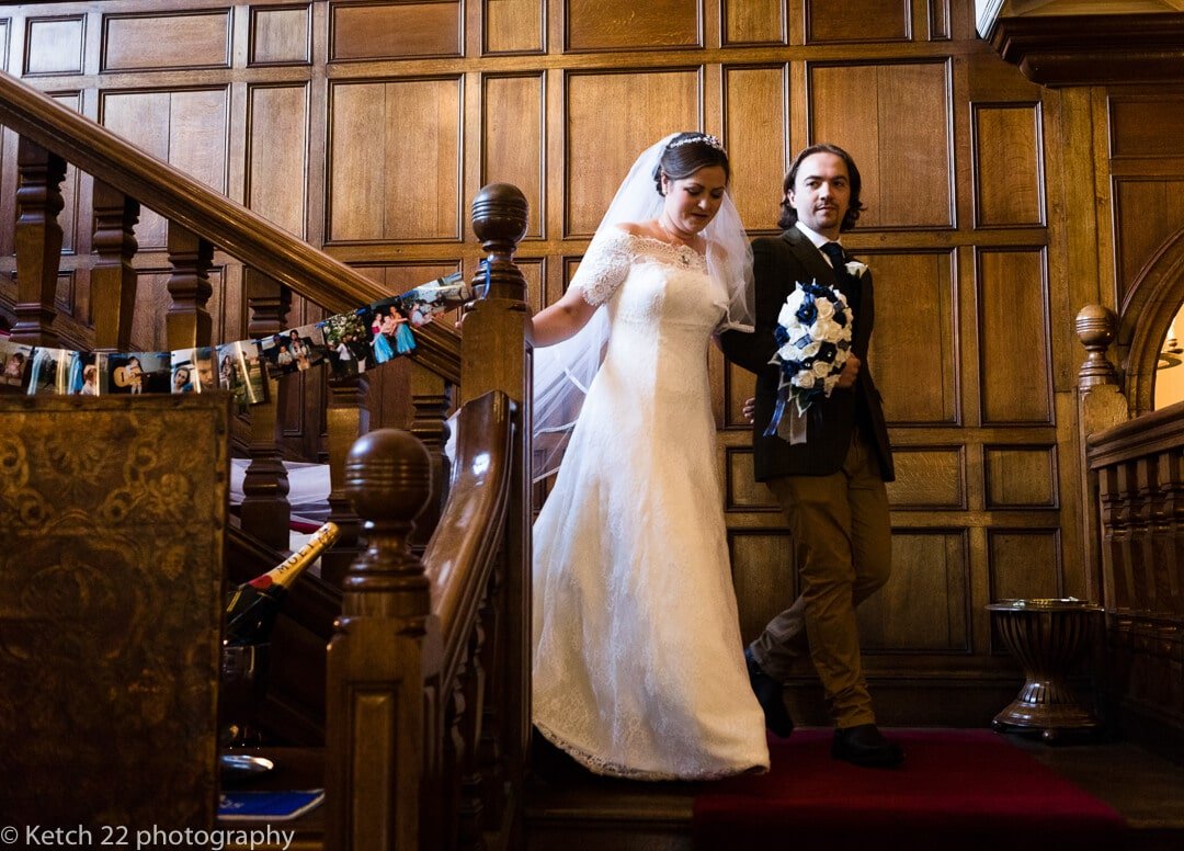 Bride coming down the stairs with brother at Country house wedding