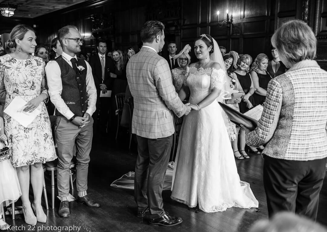 Bride and groom taking wedding vows with guests looking on