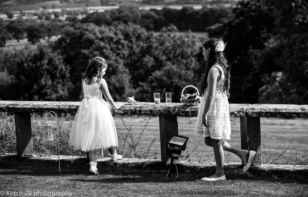 Flower girls leaning on wall in garden at summer wedding