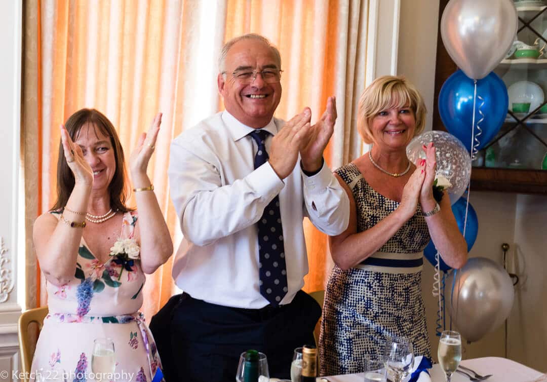 Wedding guests cheering bride and groom entering dinning room